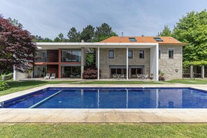 Una casa moderna de dos pisos amb una piscina al davant.