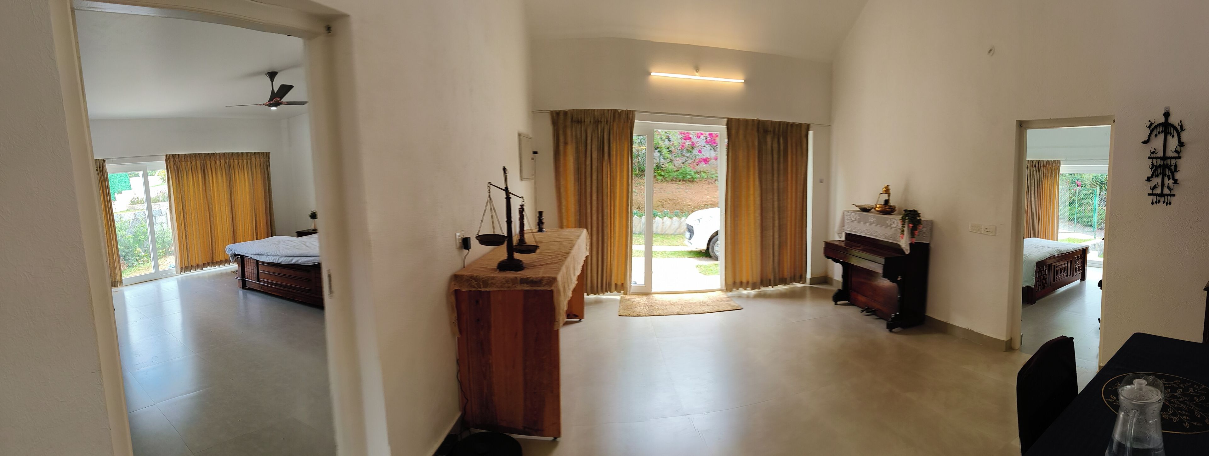 A spacious room with a bed, a desk, and a piano. There is a sliding glass door leading to an outdoor area.
