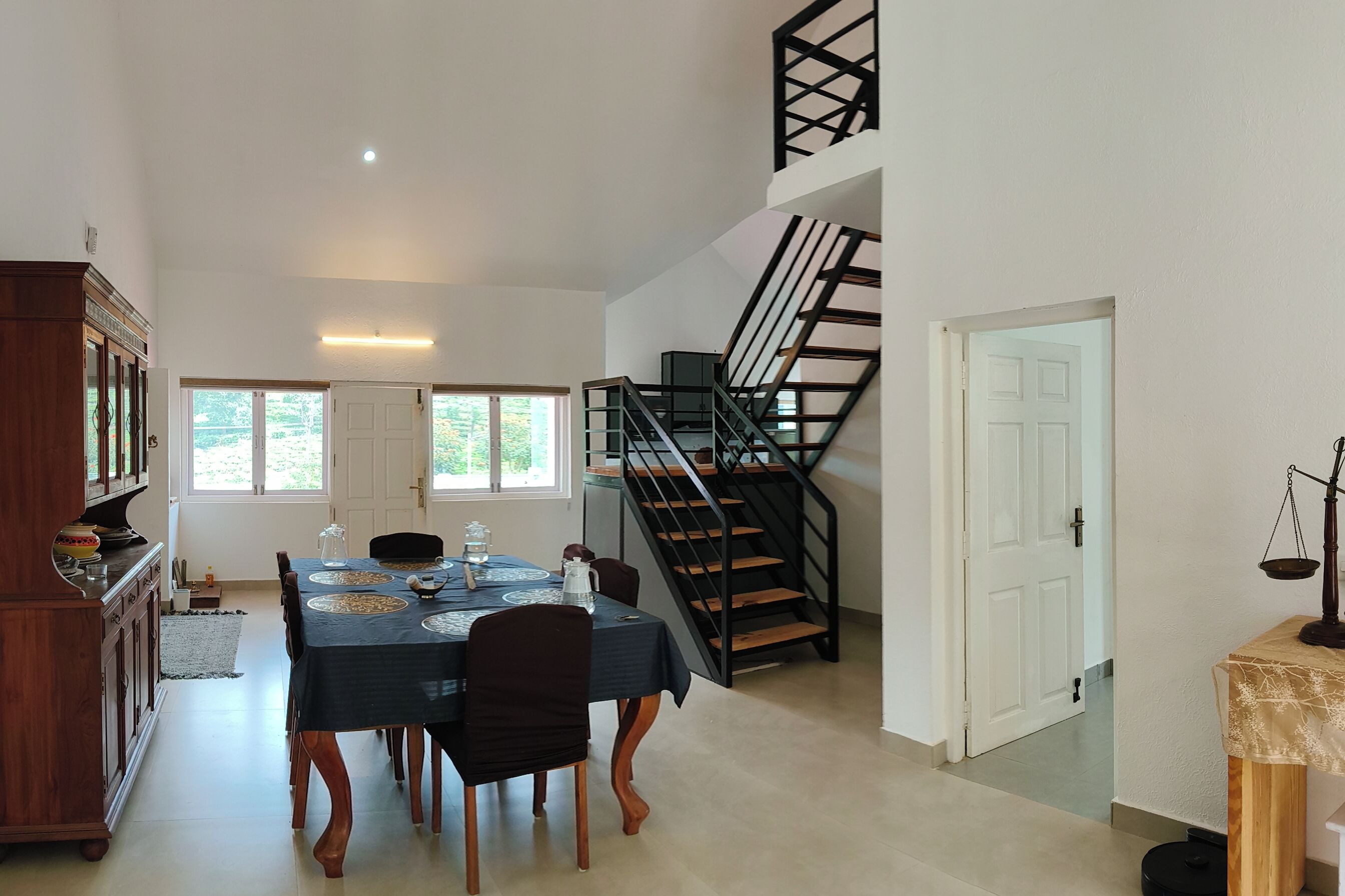 A dining area with a table set for four, a staircase, and a view of the outdoors.