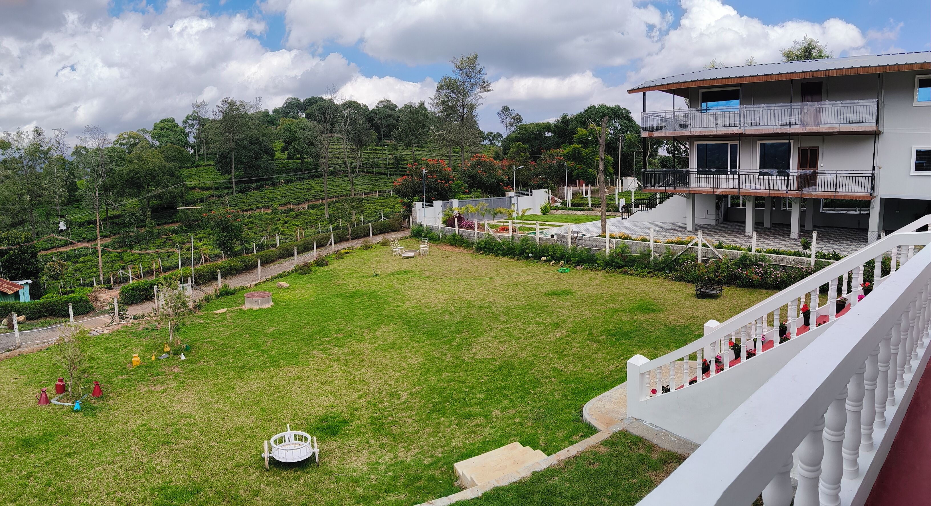 A building with a balcony overlooking a grassy area with a small pool and a fence.