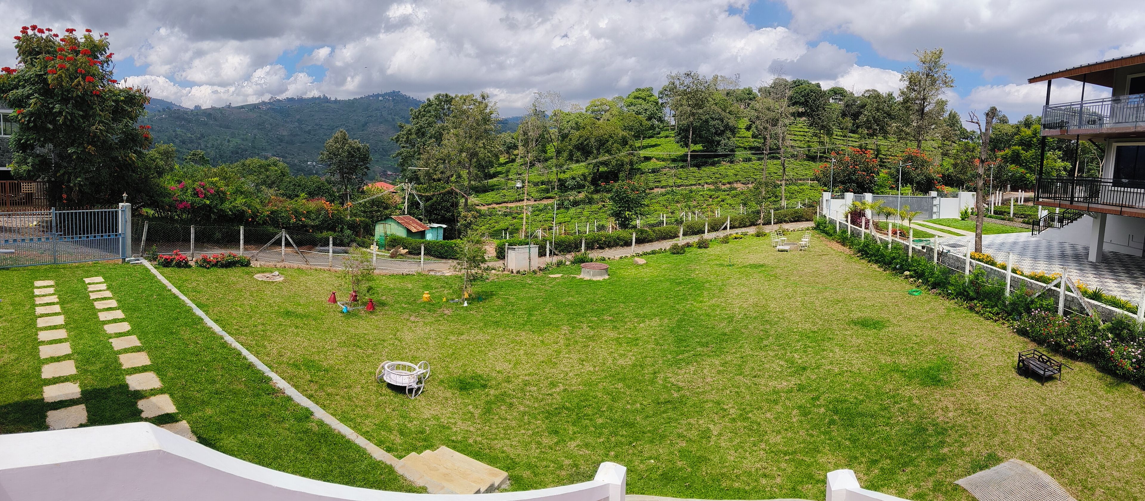 A well-maintained garden with a lawn, a small seating area, and a view of a mountainous landscape.