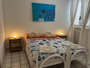 Un dormitori amb un llit, dues làmpades de nit, un quadre i una finestra amb cortines.