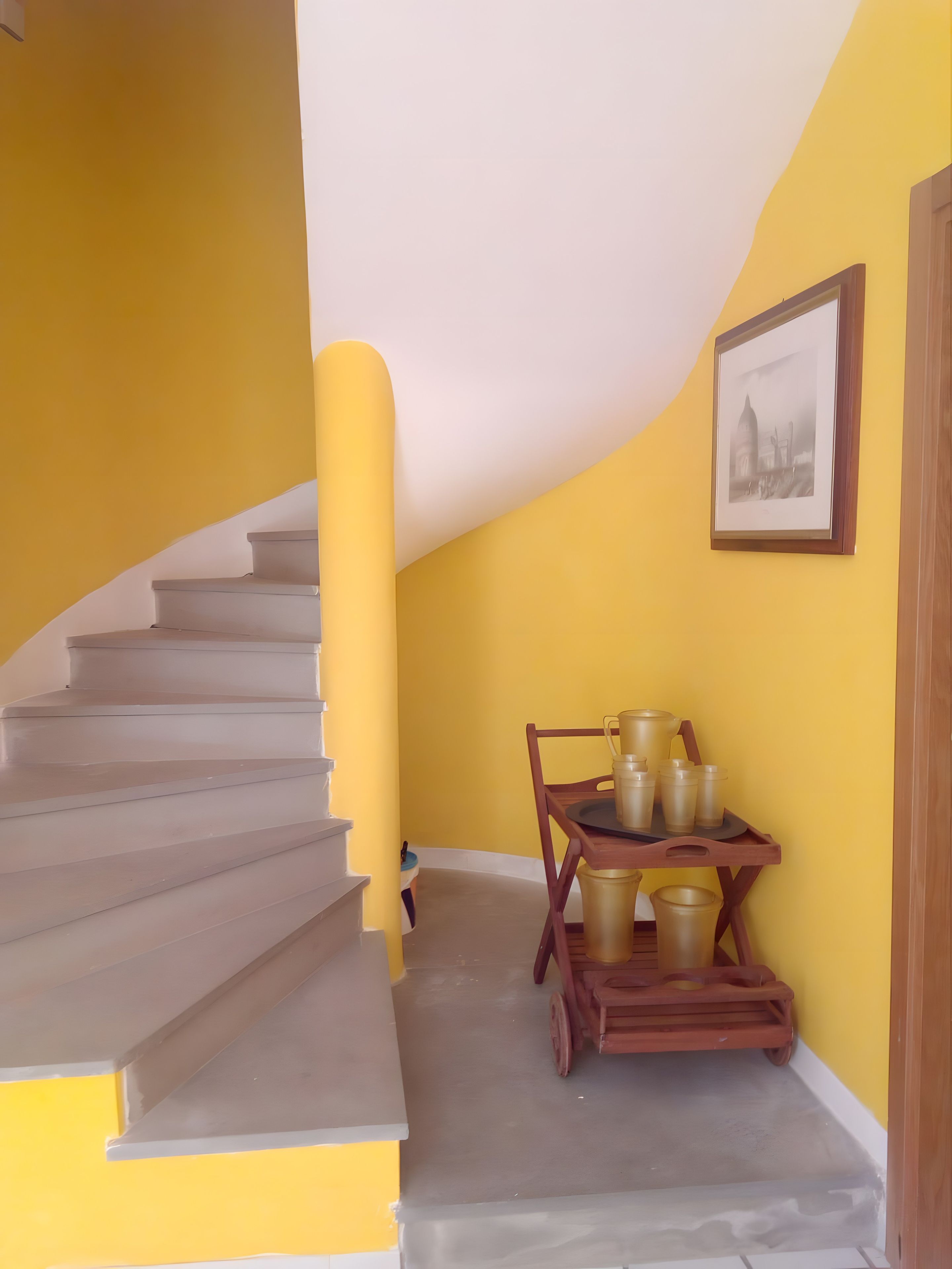 Un escalier avec un mur jaune et un tableau encadré accroché au mur.