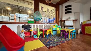 A children's play area with a slide, colorful chairs, and a play mat.