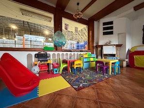A children's play area with a slide, colorful chairs, and a play mat. - Penzión SIMI (Vysoké Tatry)