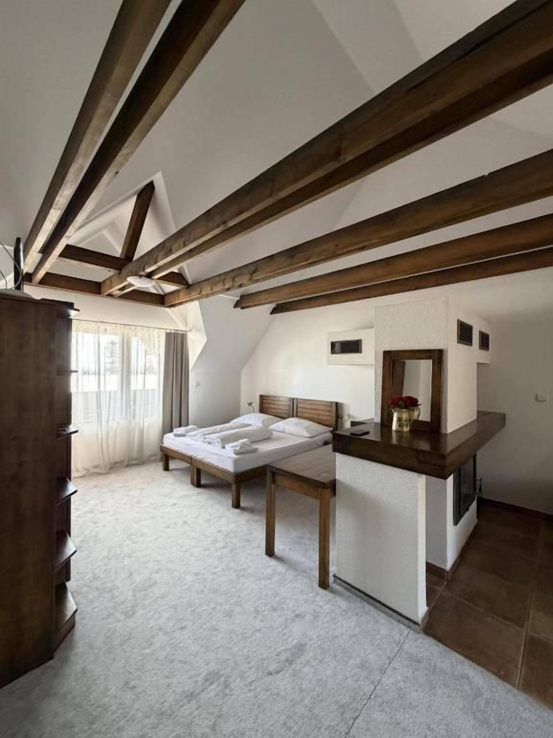 A bedroom with a wooden ceiling, a bed, a bedside table, and a dresser.