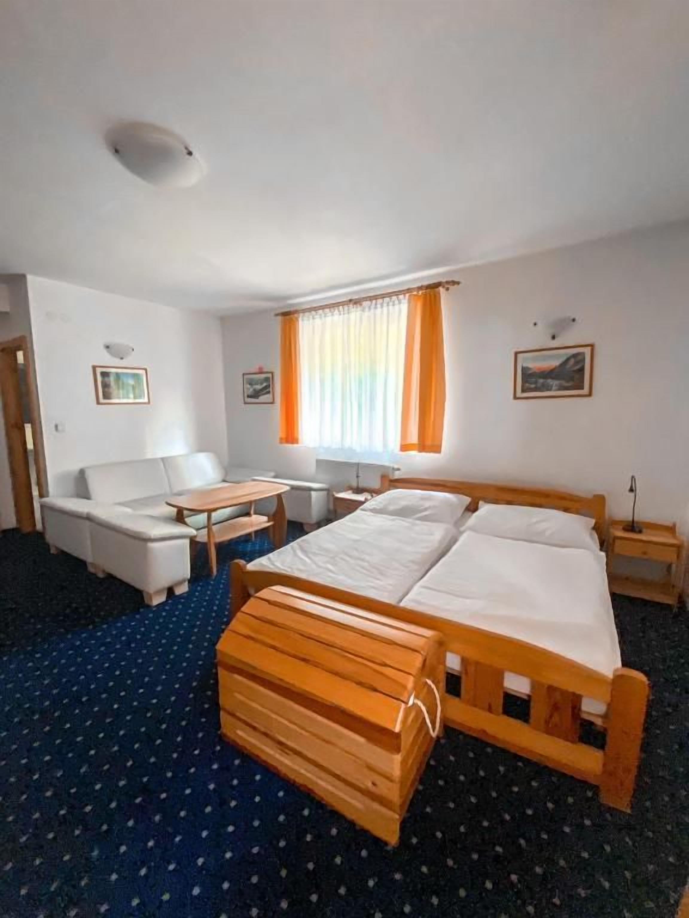 Ein Hotelzimmer mit einem Bett, einer Couch, einem kleinen Tisch und einem Fenster mit Vorhängen.