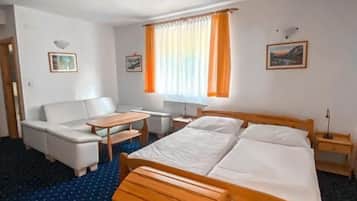 Ein Hotelzimmer mit einem Bett, einer Couch, einem kleinen Tisch und einem Fenster mit Vorhängen.