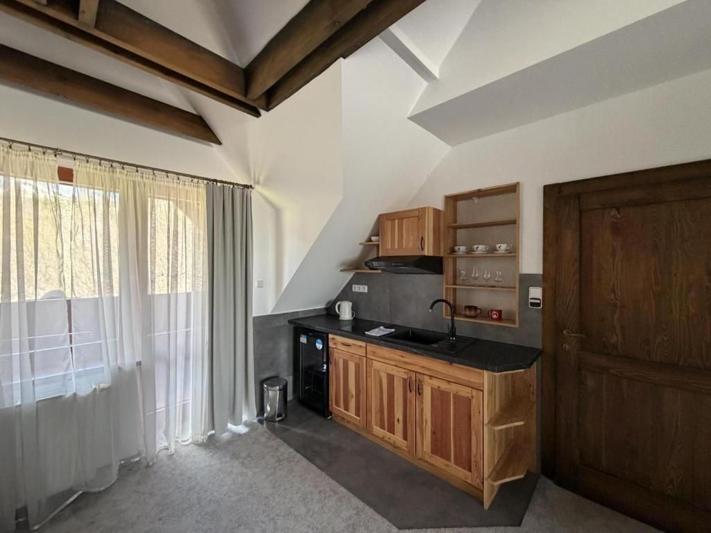 A compact kitchen with wooden cabinets, a black countertop, and a built-in oven.