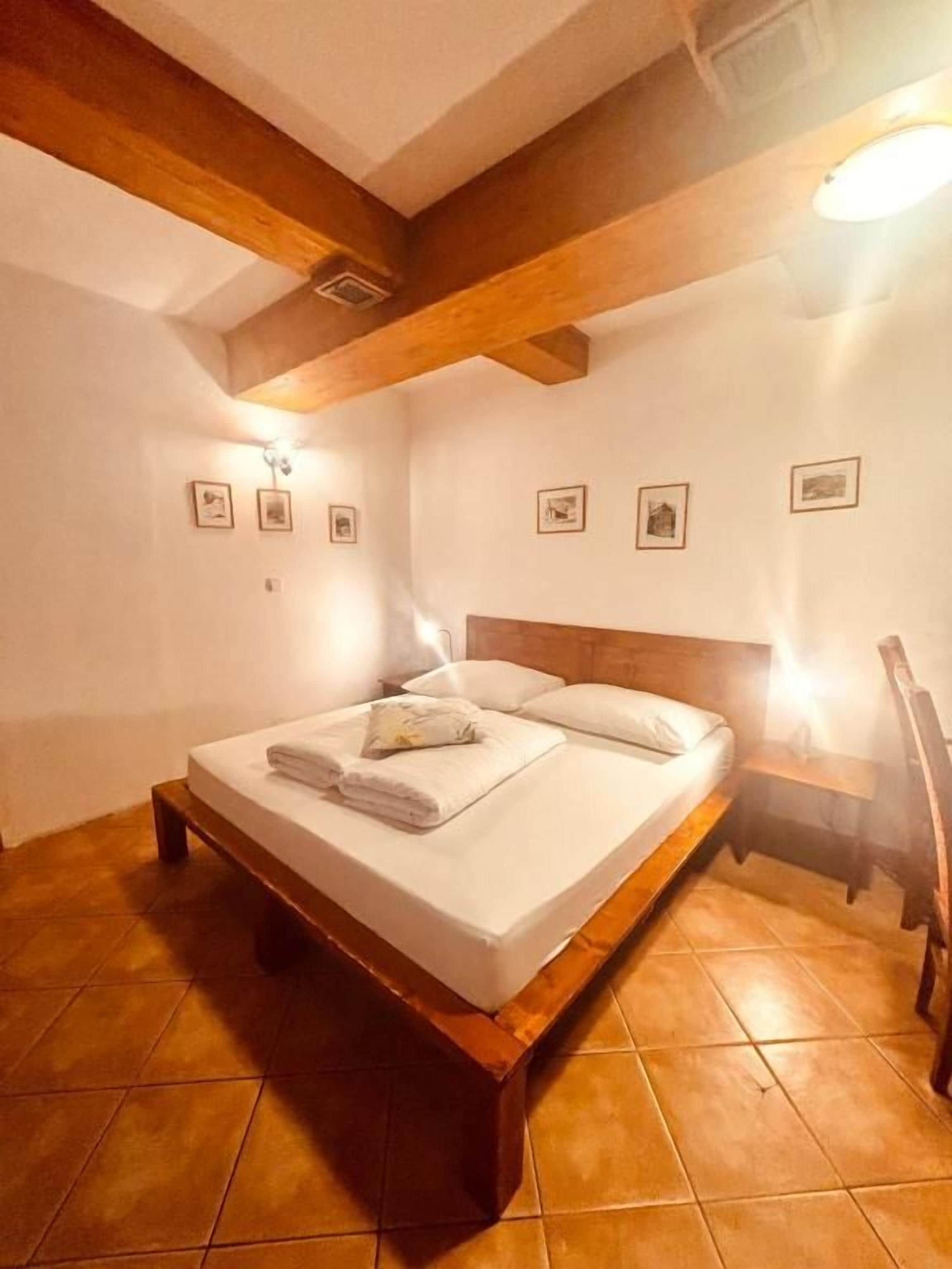 Een slaapkamer met een houten bedframe, witte lakens en een hoofdbord.