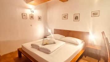 Een slaapkamer met een houten bedframe, witte lakens en een hoofdbord.