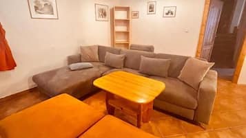 A living room with a sectional sofa, a wooden coffee table, and orange ottomans.