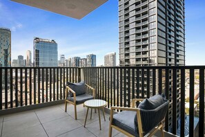 A balcony with two chairs and a small table, overlooking a cityscape with modern buildings. - High-rise 2-bed Apartment Near South Melbourne (Melbourne)