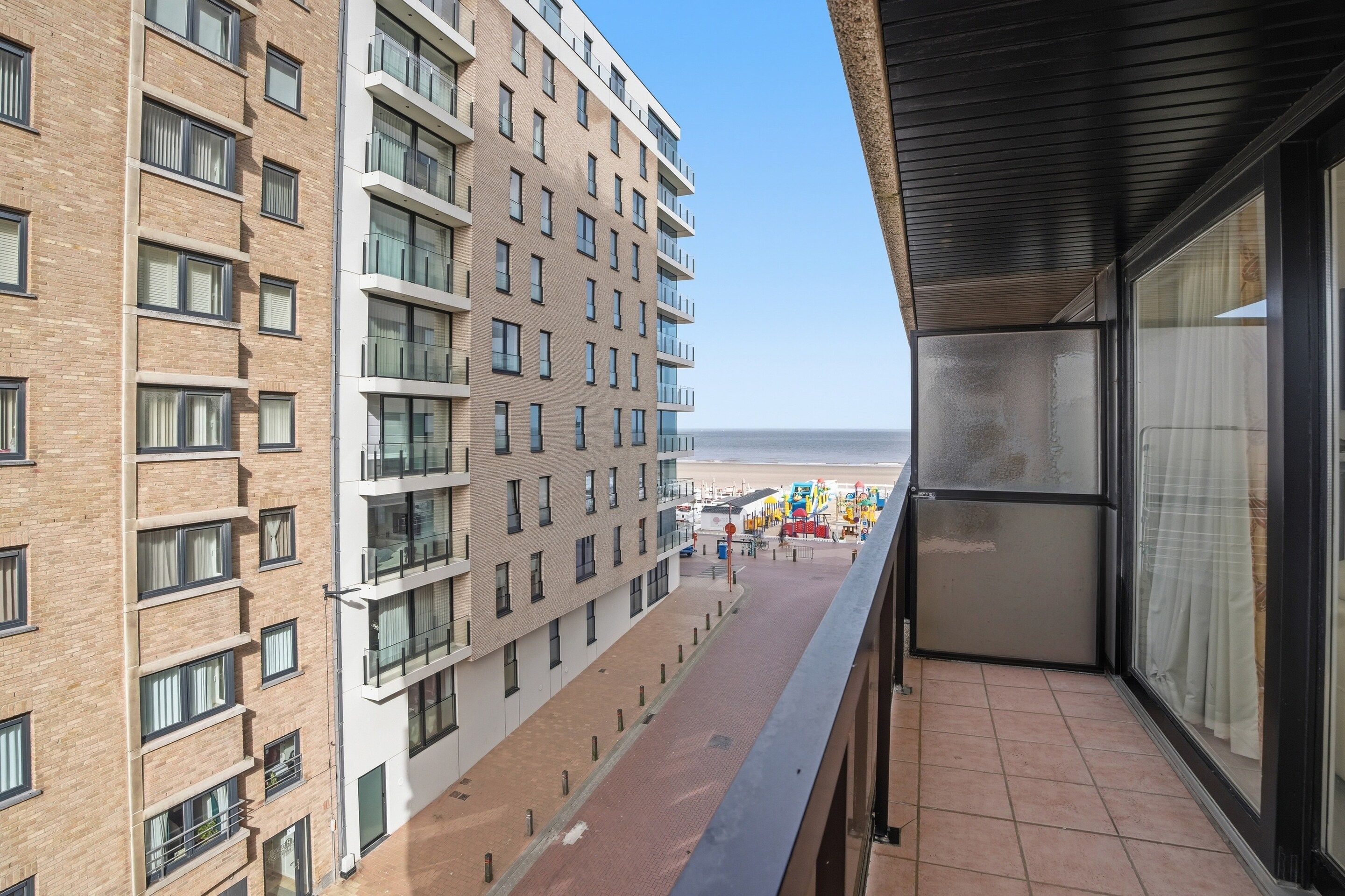 Ein Hochhaus mit mehreren Balkonen mit Blick auf einen Strand, ausgestattet mit Strandliegen und Sonnenschirmen.