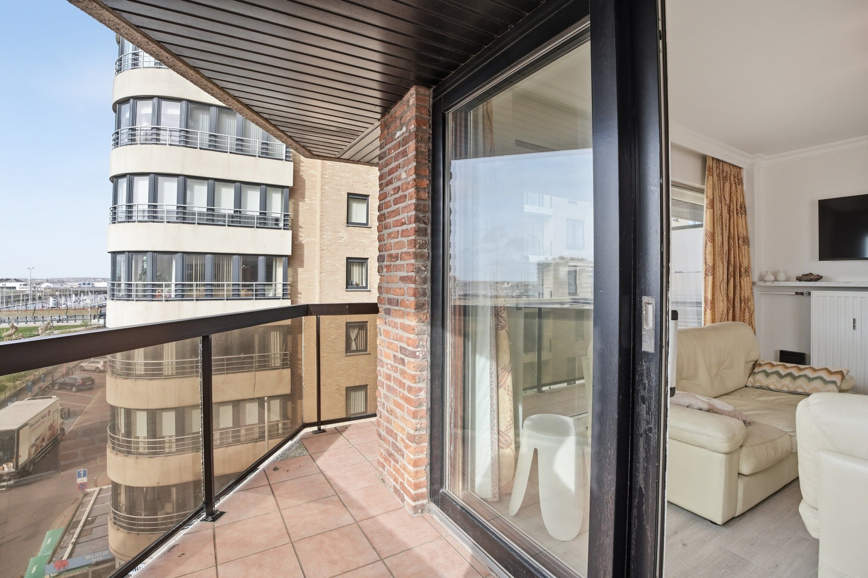 A balcony with a view of a cityscape, a sofa, and a television.