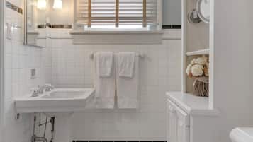 A bathroom with a white sink, a mirror, and a window with blinds.