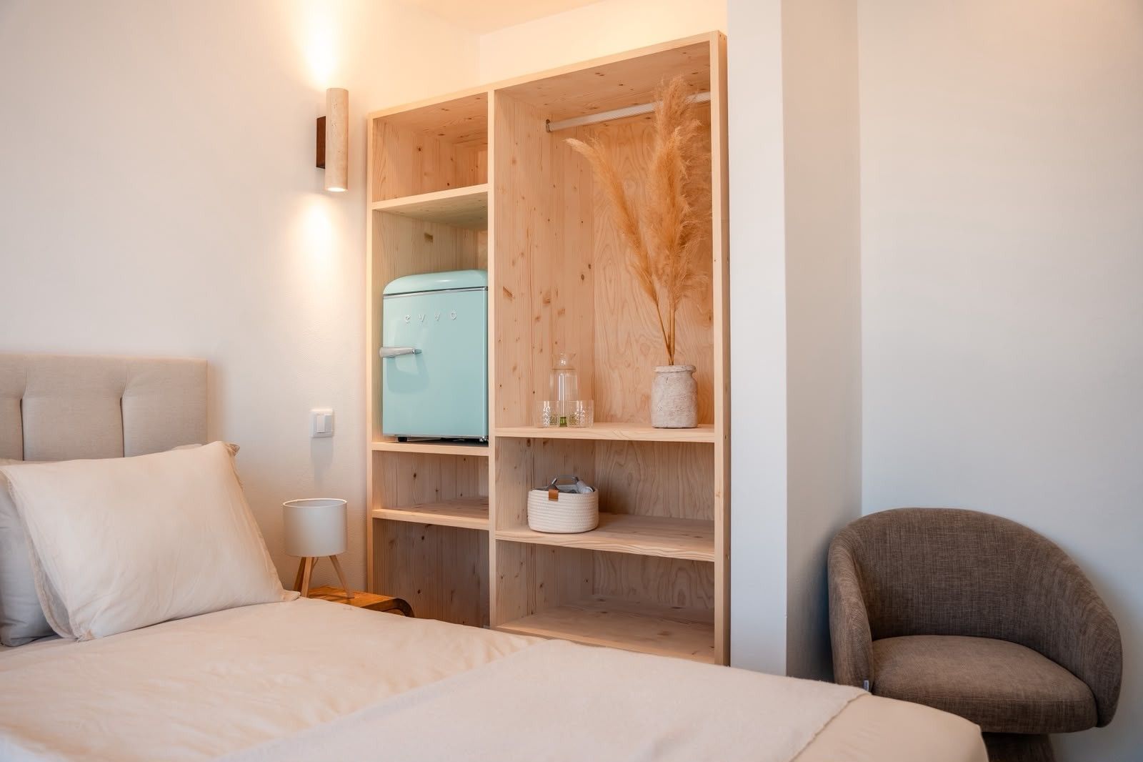 Ein Schlafzimmer mit einem Bett, einem Kleiderschrank, einem Sessel und einem kleinen Tisch mit einer Lampe.