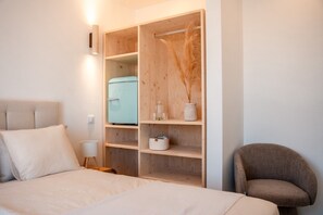 Ein Schlafzimmer mit einem Bett, einem Kleiderschrank, einem Sessel und einem kleinen Tisch mit einer Lampe.
