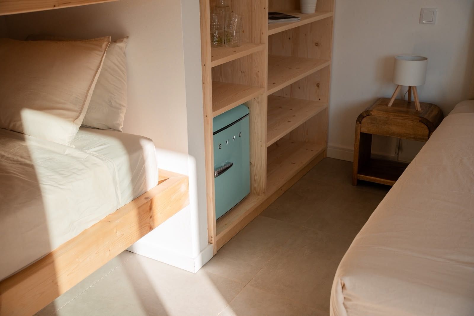 A bedroom with a bunk bed, a built-in wardrobe, and a bedside table with a lamp.