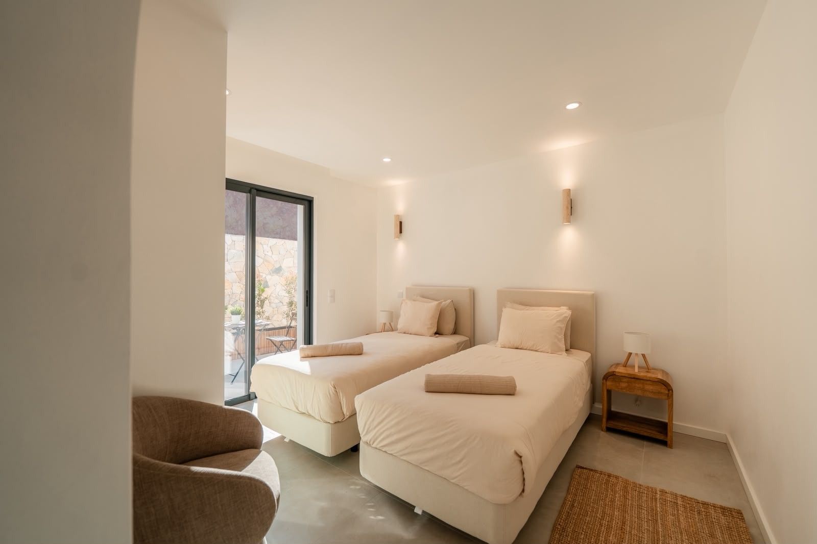 Ein modernes Schlafzimmer mit zwei Betten, einer Sitzecke und Blick ins Freie.