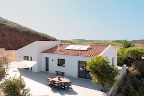 Ein modernes Haus mit Flachdach, einer Terrasse mit Tisch und Stühlen und Blick auf die Landschaft.