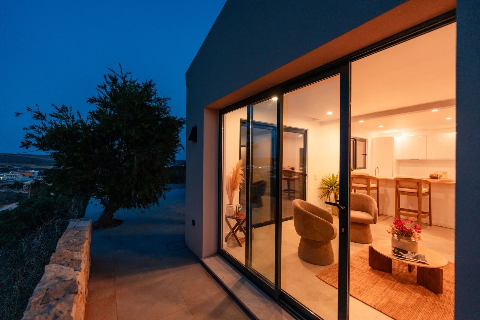 A modern house with a glass door leading to a living area with a sofa and a coffee table.