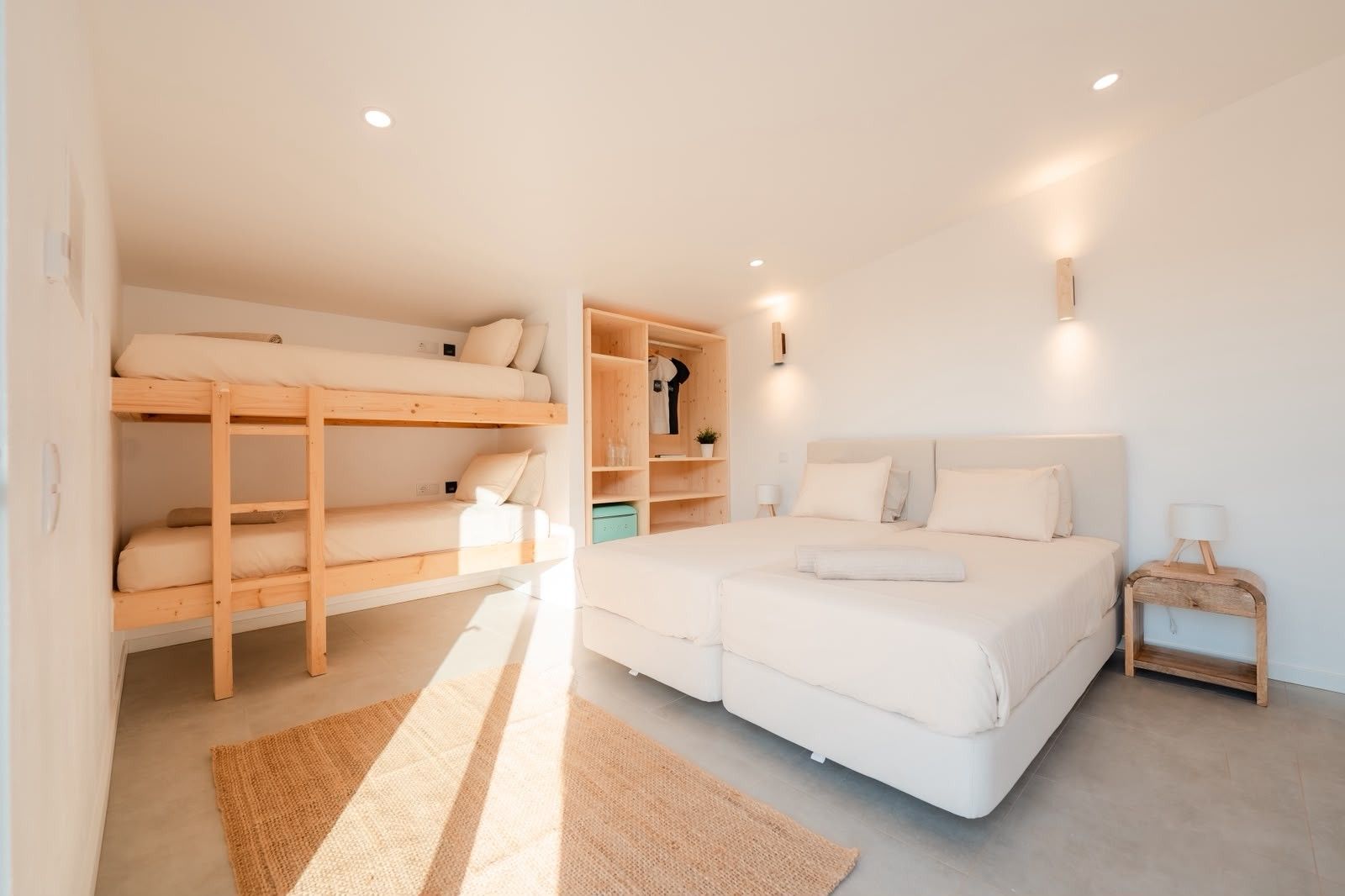 Ein Schlafzimmer mit einem Etagenbett, einem Doppelbett, einem Nachttisch mit Lampe und einem Kleiderschrank.