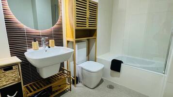 Ein modernes Badezimmer mit einem großen Waschbecken, einer Toilette und einer Badewanne.