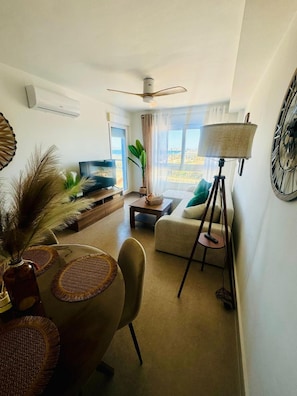 Una sala de estar moderna con un sofá, una mesa de centro, un televisor y una lámpara.