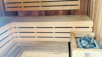 Un sauna avec des bancs en bois et un récipient en métal pour l’eau.