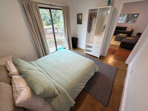 Een slaapkamer met een bed, een kledingkast, een zithoek met een bank en uitzicht op de omgeving.