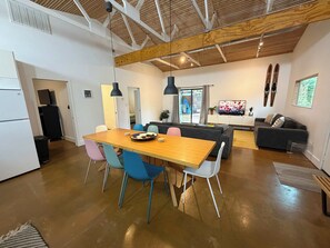 A modern living space with a dining area, a sofa, and a TV. - PRD 2420 Rio Vista: Escape to the beautiful Guadalupe River (New Braunfels)