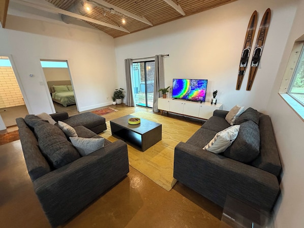 Een moderne woonkamer met twee banken, een salontafel en een televisie op een wit meubel.