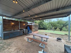 Een terras buiten met een inbouwkeuken, een barbecue en een picknicktafel.