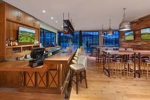 Ein moderner Barbereich mit Holztresen, Barhocker und einer langen Theke mit einer Barista-Station.
