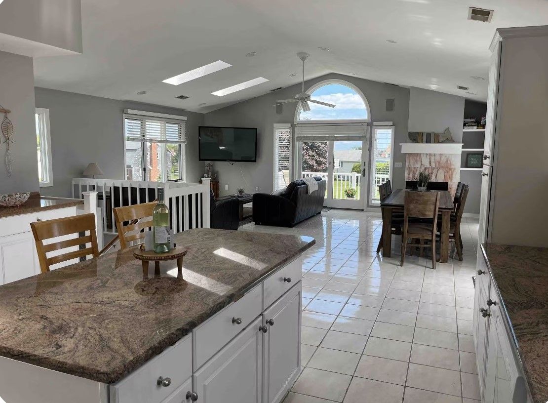Una cocina amplia con una isla grande, muebles blancos y una zona de comedor con mesa y sillas.