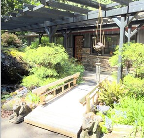 A wooden deck leading to a stone building with a covered walkway overhead.