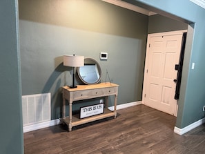 A hallway with a wooden console table, a lamp, a mirror, and a sign that reads 'THIS IS US blended & blended.' - Spacious Beaumont Retreat Spacious + Home Gym (Beaumont)