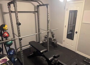 A home gym with a squat rack, bench, and various weights. - Spacious Beaumont Retreat Spacious + Home Gym (Beaumont)