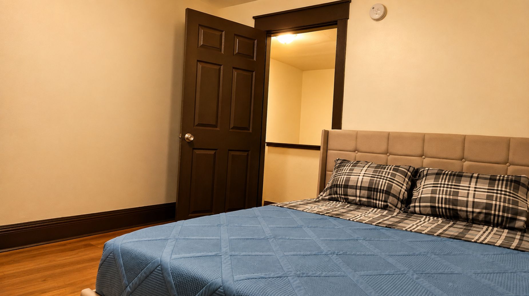 Une chambre à coucher avec un lit, une porte et un luminaire fixé au mur.
