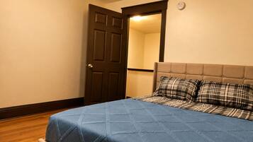 Une chambre à coucher avec un lit, une porte et un luminaire fixé au mur.