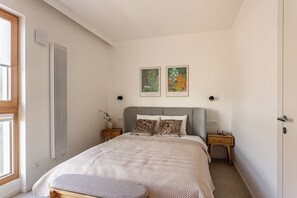 A bedroom with a bed, two nightstands, a radiator, and two framed artworks on the wall. - Towarowa Square V P&O Apartments (Warszawa)