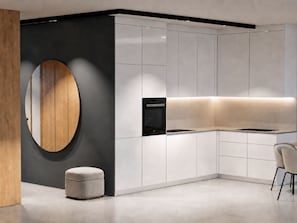 Una cocina moderna con armarios blancos, horno empotrado y una pared decorativa de madera redonda.