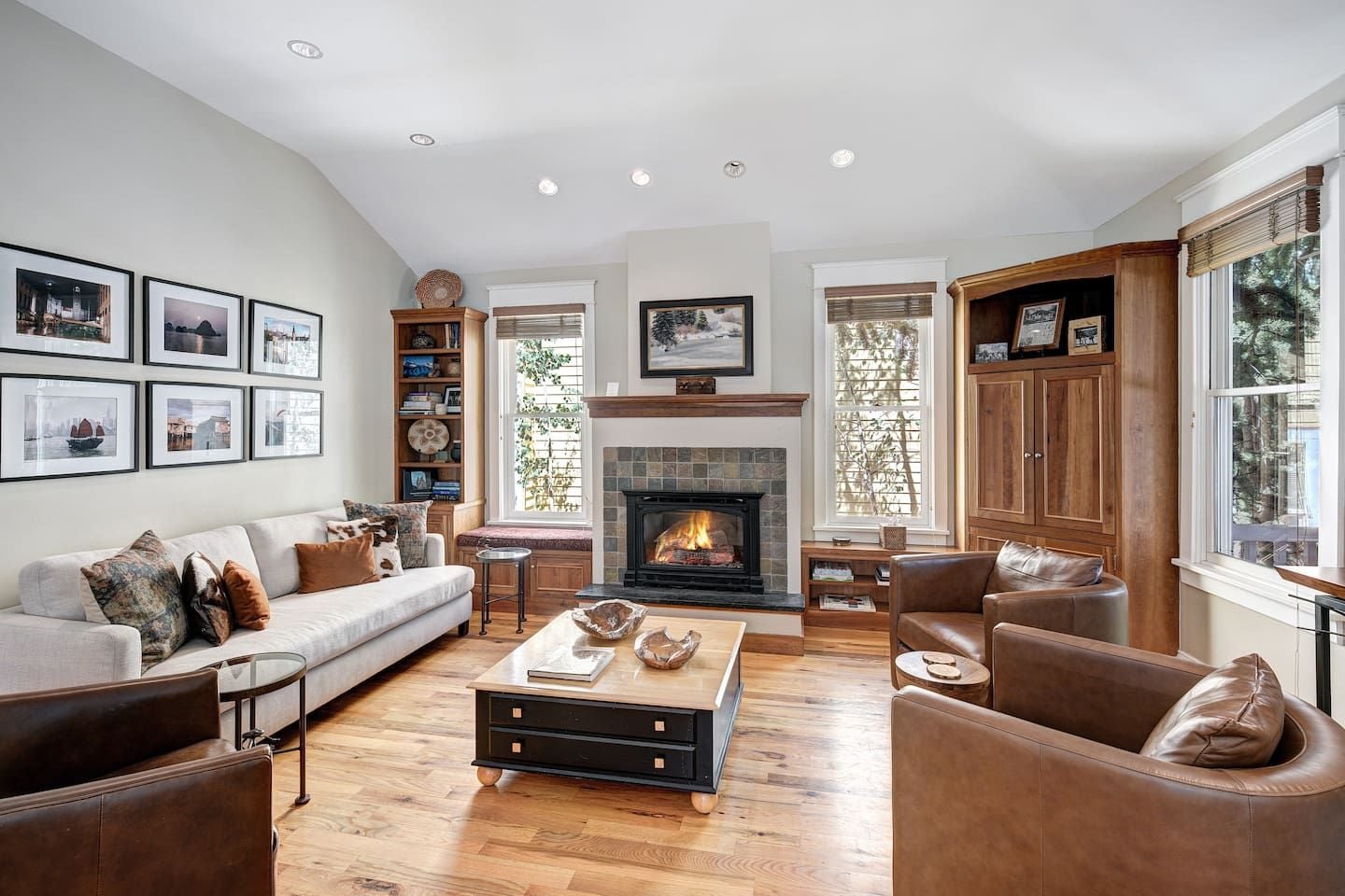 A spacious living room with a fireplace, a sofa set, a coffee table, and a bookshelf.