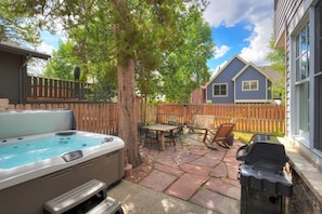 Ein Garten mit Whirlpool, Gartenmöbeln und einem Grill.