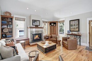 A spacious living room with a fireplace, leather furniture, and a bookshelf. - Fox Den on Historic French (Breckenridge)