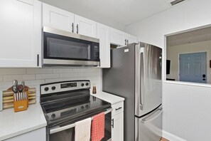 A modern kitchen with white cabinets, a stainless steel refrigerator, a microwave, and an oven. - Saltwater Pool · 3BR 2BA · Near Clearwater Beach (Clearwater)