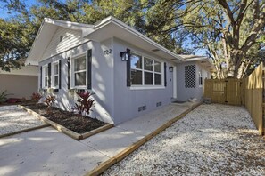 A single-story house with a number '72' on the front, a wooden fence, and a gravel driveway. - Saltwater Pool · 3BR 2BA · Near Clearwater Beach (Clearwater)