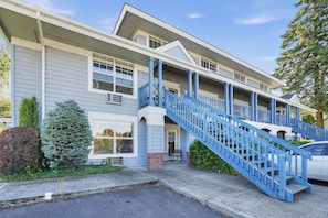 A two-story building with a blue staircase leading to the entrance. - Modern Downtown HR Condo | Walk to Waterfront (Hood River)