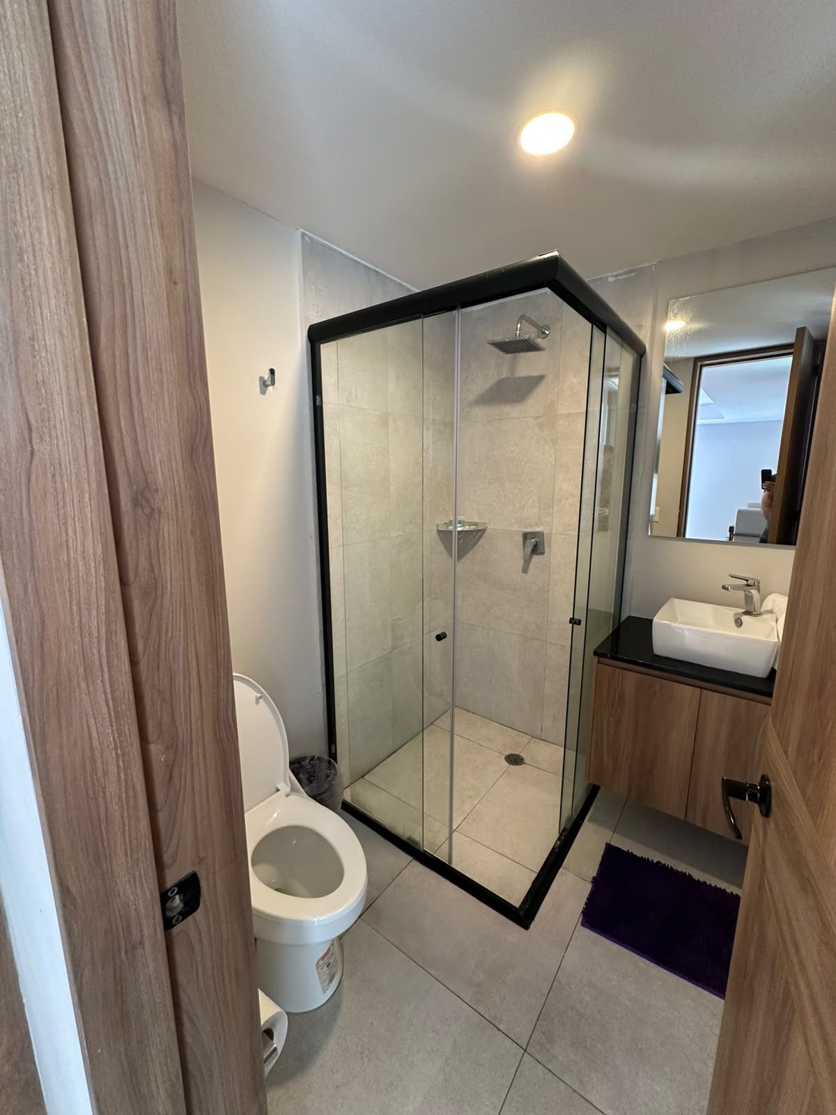 Un baño moderno con ducha de vidrio, inodoro y lavamanos.